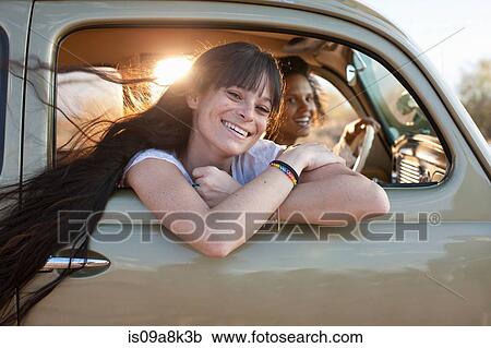 Stock Image - Young women travelling in car on road trip, portrait. Fotosearch