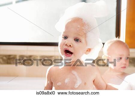Stock Image - Baby boy covered in soap suds in bath. Fotosearch