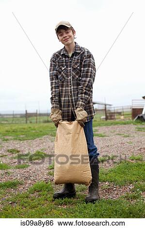Stock Photograph - Boy carrying sack of feed. Fotosearch