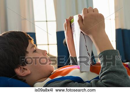 Boy lying on bed reading book View Large Photo Image Stock Image - Boy lying on bed reading book. Fotosearch