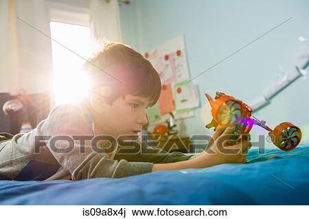 Boy lying on bed with toy View Large Photo Image Stock Image - Boy lying on bed with toy. Fotosearch