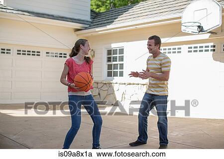 Stock Image - Brother and sister playing basketball. Fotosearch