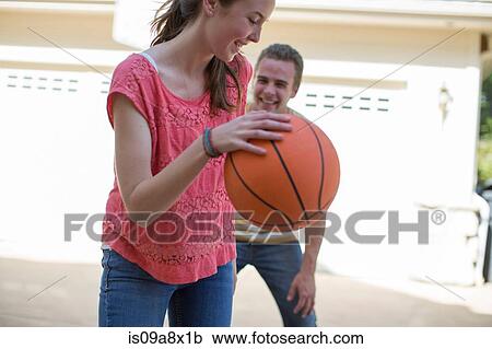 Stock Image - Brother and sister playing basketball. Fotosearch