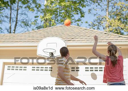 Stock Image - Brother and sister playing basketball. Fotosearch