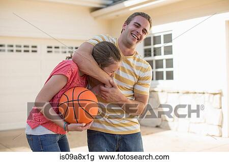 Stock Image - Brother with sister in head lock holding basketball. Fotosearch