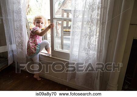 Stock Image - Child climbing over opened window. Fotosearch