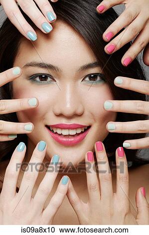 Stock Image - Close up of woman's face surrounded by hands. Fotosearch