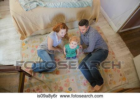 Couple lying on floor with child View Large Photo Image Stock Photography - Couple lying on floor with child. Fotosearch