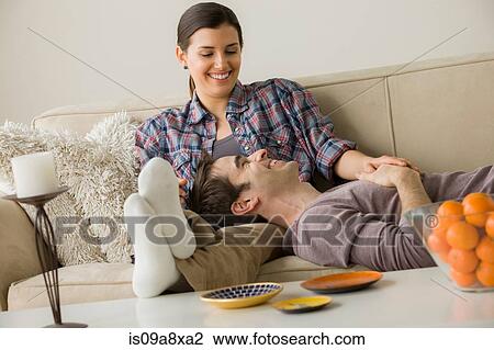 Stock Image - Couple on sofa, man with head on woman's lap. Fotosearch