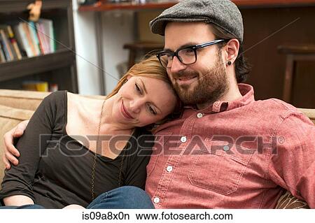 Picture - Couple sitting on sofa, arm around. Fotosearch