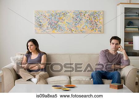 Stock Photography - Couple sitting on sofa ignoring each other. Fotosearch