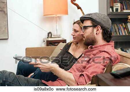Picture - Couple sitting on sofa watching television. Fotosearch