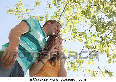 Stock Image - Couple under tree, low angle. Fotosearch