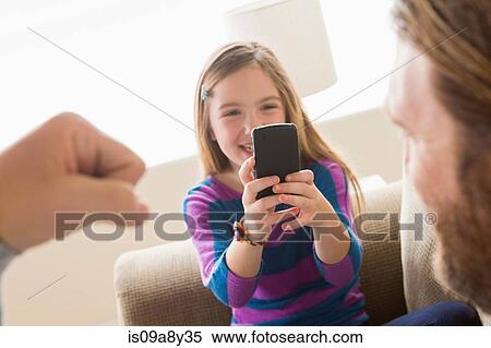 Stock Photography - Daughter photographing father with smartphone. Fotosearch