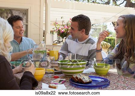 Stock Image - Family having breakfast outdoors. Fotosearch