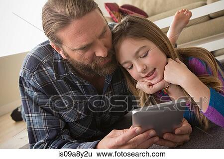 Father and daughter looking at digital tablet View Large Photo Image Stock Photograph - Father and daughter looking at digital tablet. Fotosearch