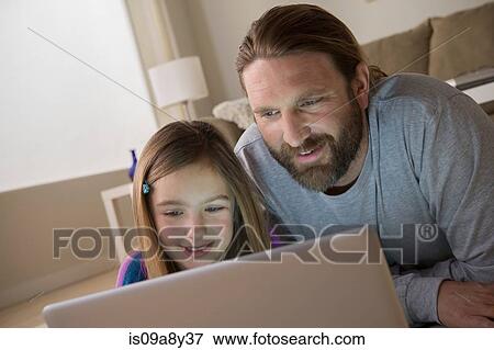 Stock Photo - Father and daughter looking at laptop. Fotosearch