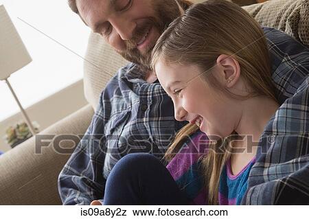 Stock Photo - Father and daughter smiling on couch. Fotosearch