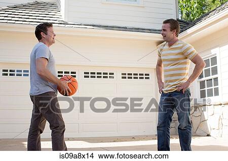Picture - Father holding basketball with adult son. Fotosearch