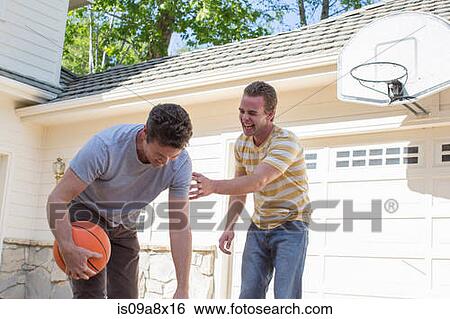 Stock Photograph - Father holding basketball with adult son laughing. Fotosearch