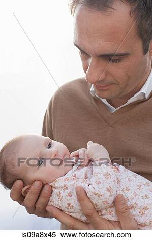 Stock Photography - Father holding newborn baby daughter. Fotosearch