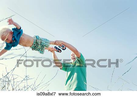 Stock Photo - Father spinning son in field, low angle. Fotosearch