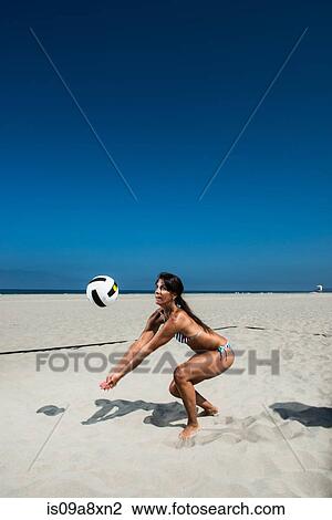 Stock Image - Female beach volleyball player digging ball. Fotosearch