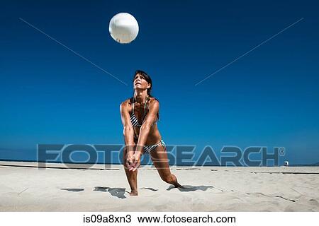 Stock Image - Female beach volleyball player digging ball. Fotosearch