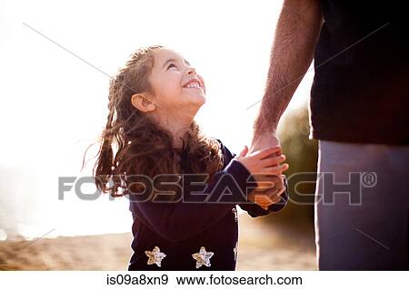 Stock Photo - Girl holding father's hand, looking up. Fotosearch