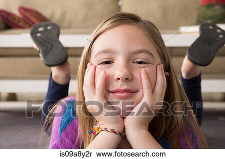 Stock Photography - Girl lying on stomach looking at camera. Fotosearch