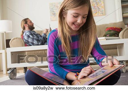 Stock Photo - Girl smiling looking at pictures in book. Fotosearch