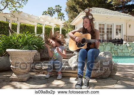 Stock Photography - Girl with older sister playing guitar. Fotosearch