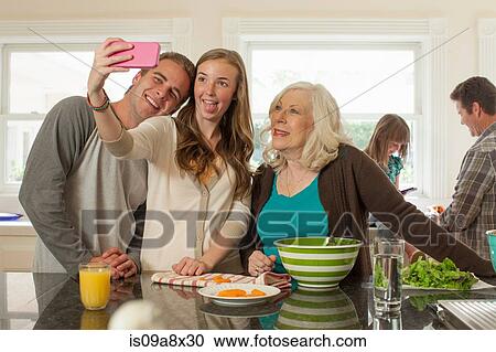 Stock Image - Grandchildren with grandmother photographing themselves. Fotosearch