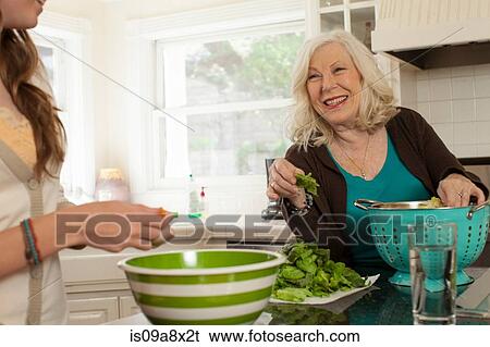 Stock Photograph - Granddaughter with grandmother preparing salad. Fotosearch