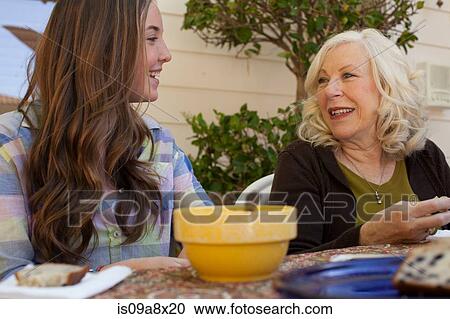 Stock Image - Grandmother and granddaughter having breakfast outdoors. Fotosearch