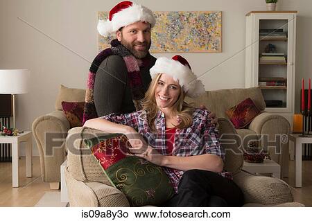 Picture - Husband and wife in Santa hat looking at camera. Fotosearch