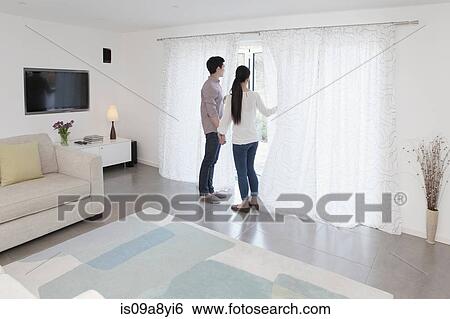 Stock Photograph - Husband and wife looking out of glass door. Fotosearch