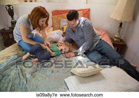 Stock Image - Husband and wife playing with child. Fotosearch