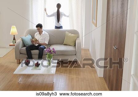 Stock Image - Husband and wife relaxing in living room. Fotosearch