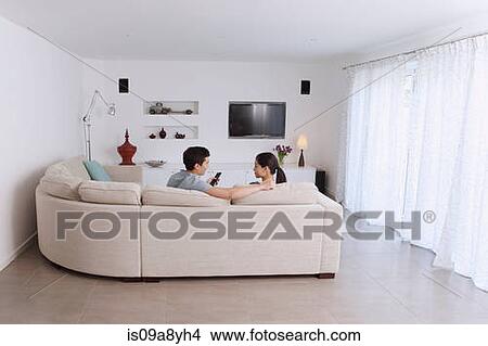 Husband and wife relaxing on corner sofa in living room View Large Photo Image Picture - Husband and wife relaxing on corner sofa in living room. Fotosearch
