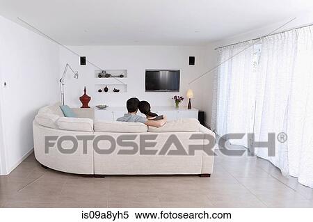 Stock Photography - Husband and wife relaxing on corner sofa in living room. Fotosearch