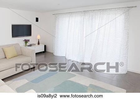 Stock Image - Living room curtains moving slightly in the breeze. Fotosearch