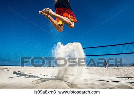 Stock Photo - Male beach volleyball player jumping mid air. Fotosearch