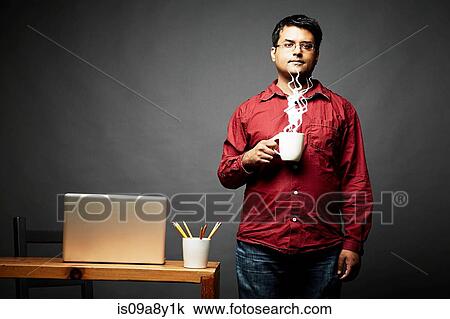 Stock Image - Man holding cup of steaming hot beverage. Fotosearch