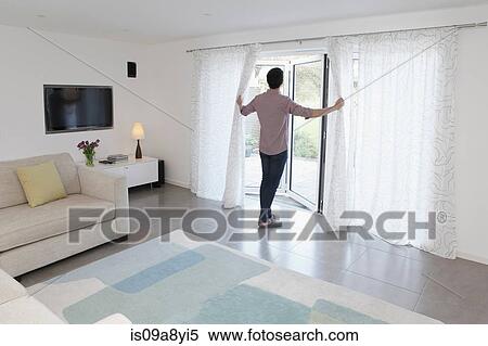 Stock Photography - Man looking out of glass door. Fotosearch