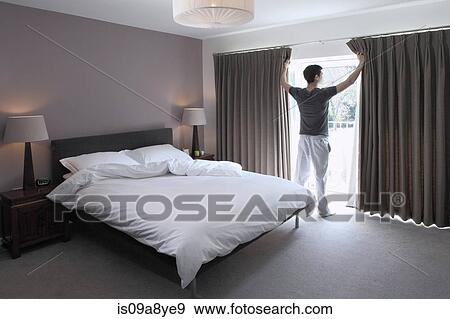 Stock Photo - Man looking through glass door of bedroom. Fotosearch