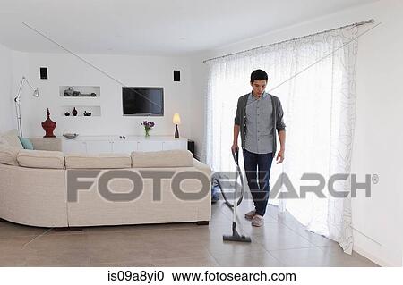 Stock Image - Man vacuuming living room floor. Fotosearch