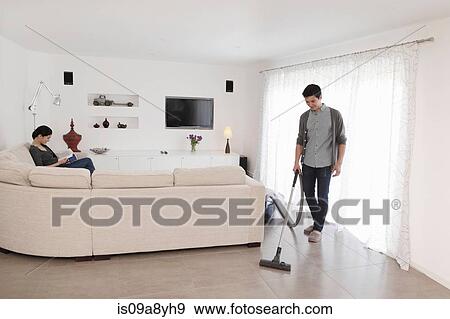 Man vacuuming living room floor View Large Photo Image Stock Photo - Man vacuuming living room floor. Fotosearch