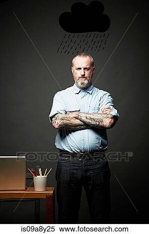 Stock Photography - Man with arms crossed standing under dark rain cloud. Fotosearch