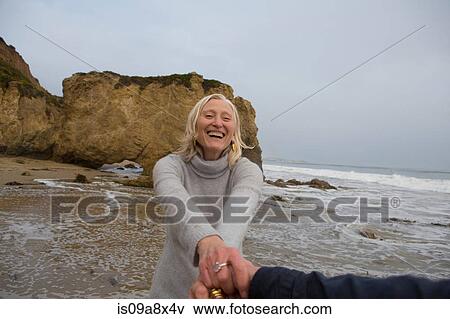 Stock Photo - Mature couple holding hands on beach. Fotosearch